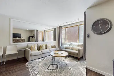 a living room with a couch and a clock on the wall at Cozy Coyote Fork Condo in Truckee