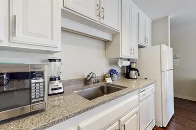a kitchen with white cabinets and a sink and a refrigerator at Cozy Coyote Fork Condo in Truckee