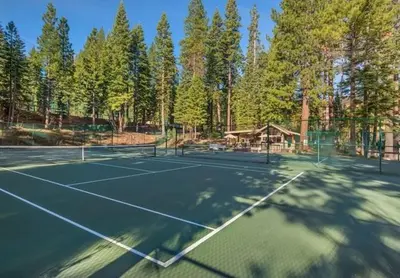 a tennis court with trees in the background at Northstar Conifer Luxury Home home in Truckee