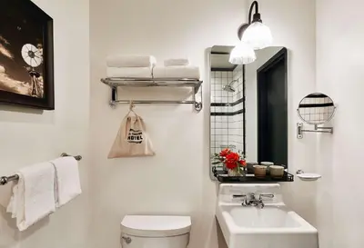a bathroom with a toilet and a sink and a mirror at El Capitan Hotel in Merced