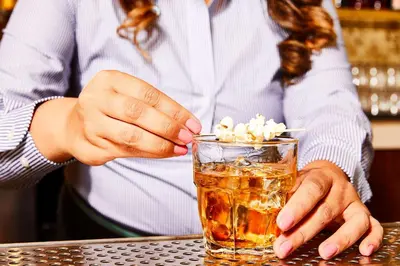 a person is holding a drink in a glass at El Capitan Hotel in Merced