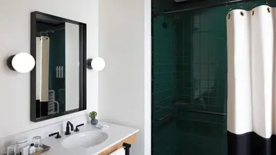 a bathroom with a sink and a shower with green tiles at El Capitan Hotel in Merced