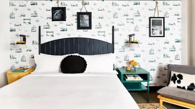a bedroom with a bed and a wall of wallpaper at El Capitan Hotel in Merced