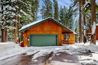 a wooden building with a garage in the snow at Piney Retreat in Carnelian Bay