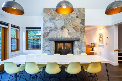 a living room with a stone fireplace and a table and chairs at Cedar Crest - Eagle Cottage 8 in Homewood