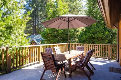 a wooden table and chairs with an umbrella on a deck at Cedar Crest - Eagle Cottage 8 in Homewood