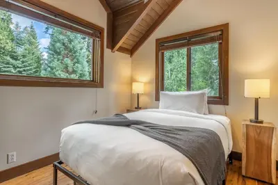 a bedroom with a large bed and two windows at Cedar Crest - Owl Cottage 9 in Homewood