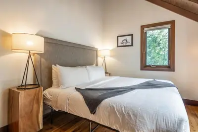 a bedroom with a bed with two lamps and a window at Cedar Crest - Owl Cottage 9 in Homewood