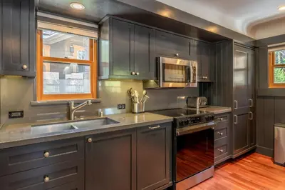 a kitchen with gray cabinets and stainless steel appliances at Cedar Crest - Woodpecker Cottage 7 in Homewood