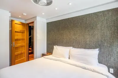 a bedroom with a white bed and a wall at Cedar Crest - Woodpecker Cottage 7 in Homewood