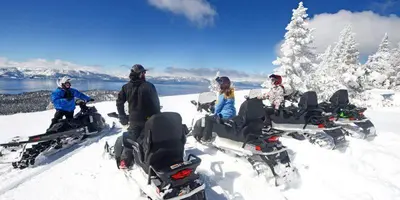 a group of people sitting in the snow on snowmobiles at LUXE 4 Blue Diamond Lake Tahoe Lodge in Stateline