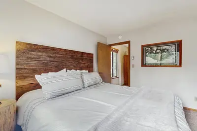 a bedroom with a white bed with a wooden headboard at Whispering Pines in Shaver Lake
