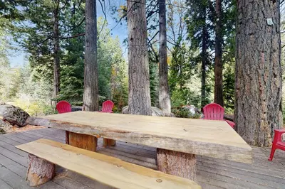 a wooden picnic table and chairs on a deck with trees at Whispering Pines in Shaver Lake