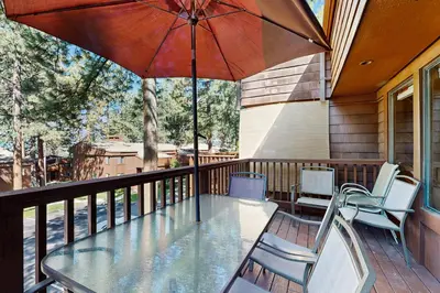 a table and chairs on a balcony with an umbrella at Private Beach Retreat in Zephyr Cove