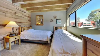 two beds in a room with a window at Beautiful 2 BR with 2 Lofts SLOPESIDE! in Mammoth Lakes