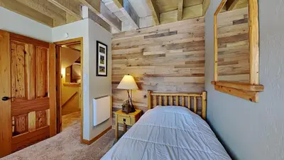 a bedroom with a bed and a wooden wall at Beautiful 2 BR with 2 Lofts SLOPESIDE! in Mammoth Lakes
