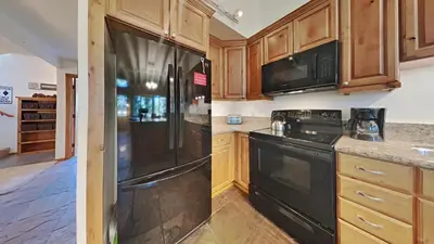 a kitchen with wooden cabinets and a black refrigerator at Spacious 4 Bed 3 Bath Condo Great For Families! in Mammoth Lakes