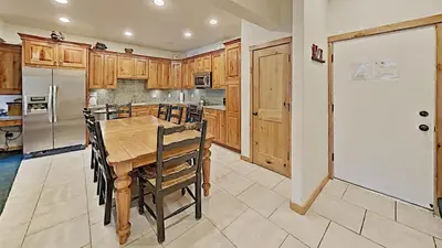 a kitchen with a wooden table and a white refrigerator at Spacious Two Bedroom Condo with Loft! in Mammoth Lakes