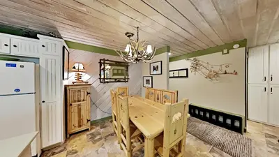 a kitchen with a wooden table and a refrigerator at Beautiful Remodeled One Bedroom Condo! in Mammoth Lakes