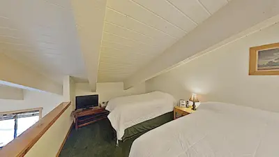 a bedroom with two beds and a flat screen tv at Cozy One Bedroom Condo with Loft! in Mammoth Lakes