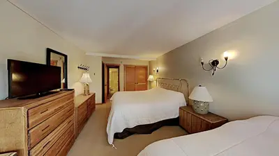 a bedroom with two beds and a flat screen tv at Spacious One Bedroom Condo with Full Kitchen! in Mammoth Lakes
