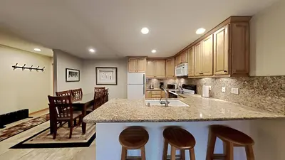 a kitchen with wooden cabinets and a kitchen island with bar stools at Spacious One Bedroom Condo with Full Kitchen! in Mammoth Lakes