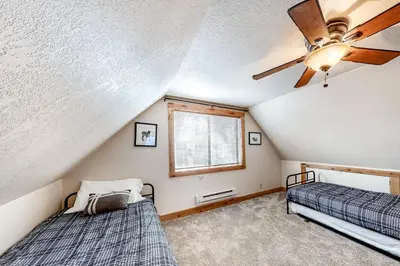 two beds in a room with a ceiling fan at Pine Cone Cabin in Soda Springs