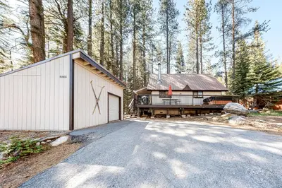 a house with a garage next to a forest at Pine Cone Cabin in Soda Springs