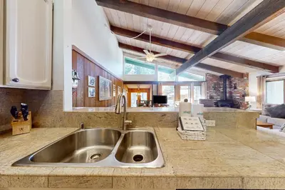 a kitchen counter with a sink and a living room at Chateau Sans Nom 29 in Mammoth Lakes