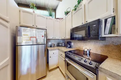 a kitchen with white cabinets and a stainless steel refrigerator at Chateau Sans Nom 29 in Mammoth Lakes