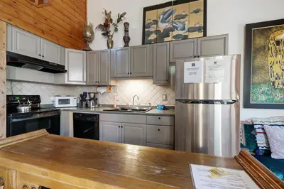 a kitchen with white cabinets and a stainless steel refrigerator at Kings Run Relaxation in Kings Beach