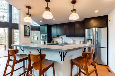 a kitchen with black cabinets and a large island with bar stools at Among the Trees in Incline Village