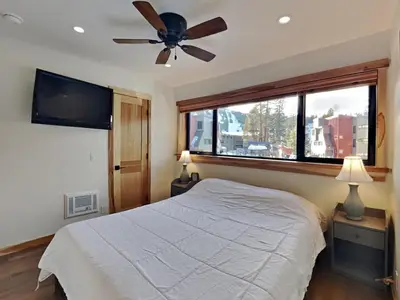 a bedroom with a bed with a ceiling fan and a window at Spacious 3 BR Condo with Loft in Mammoth Lakes