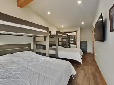 a bedroom with two bunk beds and a flat screen tv at Spacious 3 BR Condo with Loft in Mammoth Lakes