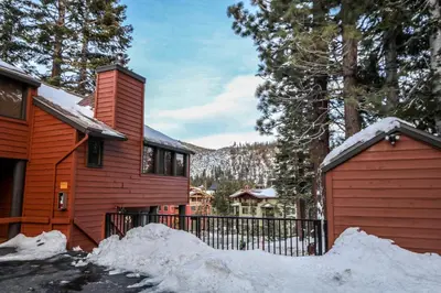 a red house with a gate and a pile of snow at Helios North #6 condo in Mammoth Lakes