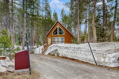 a cabin in the woods with a stone wall and a house at Poma Lane in Soda Springs