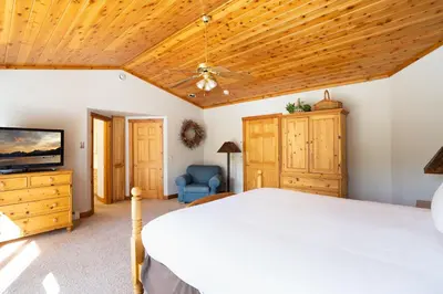 a bedroom with a white bed and a wooden ceiling at Skidder Trail Family Lodge home in Truckee