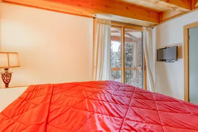 a bedroom with a red bed and a window at Northstar Perch in Truckee