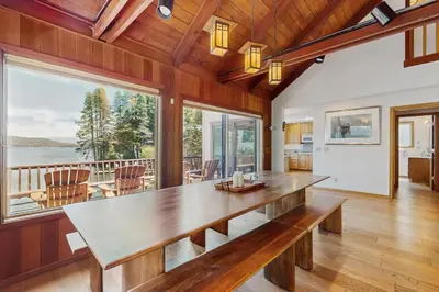 a dining room with a large wooden table and large windows at Beaver Cove Lodge in Truckee