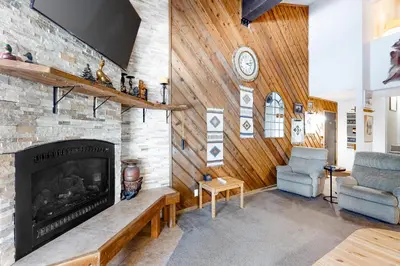 a living room with a fireplace and a chair at Crestview 36 in Mammoth Lakes