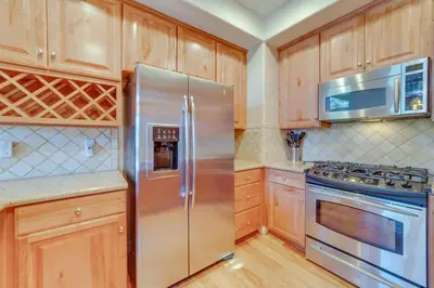 a kitchen with wooden cabinets and a stainless steel refrigerator at Central Townhome Less Than 1 Mi to The Village at Mammoth! in Mammoth Lakes