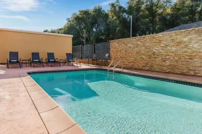 a swimming pool with chairs and a brick wall at Fairfield Inn & Suites by Marriott Oakhurst Yosemite in Oakhurst