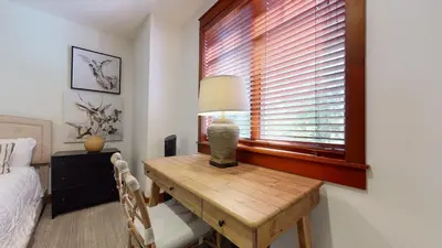 a bedroom with a table with a lamp and a window at Timbers #6 townhouse in Mammoth Lakes