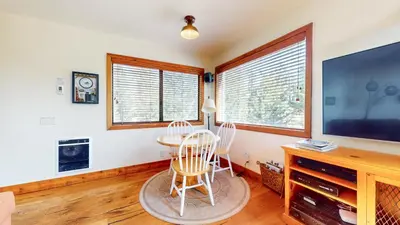 a living room with a table and chairs and a large screen tv at Rainbow Villas #1 condo in Mammoth Lakes