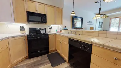 a kitchen with wooden cabinets and a black dishwasher at Mammoth Green #102 condo in Mammoth Lakes