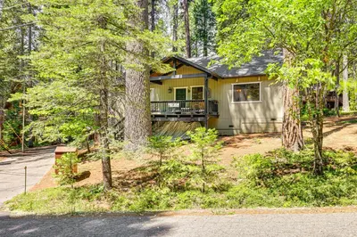 a yellow house with a balcony in the woods at Cabin with Deck and Fire Pit in Blue Lake Springs! in Arnold