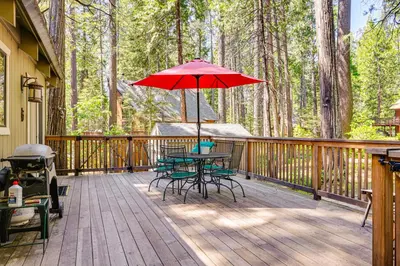 a deck with a table and chairs and an umbrella at Cabin with Deck and Fire Pit in Blue Lake Springs! in Arnold