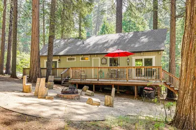 a house with a large deck in the woods at Cabin with Deck and Fire Pit in Blue Lake Springs! in Arnold