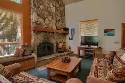 a living room with a stone fireplace and a tv at 92R Jolie Cabin in North Wawona