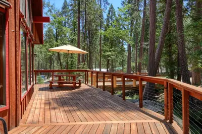 a wooden deck with a bench and an umbrella at 92R Jolie Cabin in North Wawona